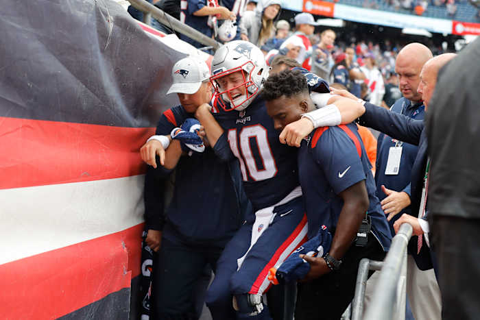 New England Patriots quarterback Mac Jones (10) is helped off the field after suffering a leg injury with less than two minutes to play in the second half of an NFL football game against the Baltimore Ravens, Sunday, Sept. 25, 2022, in Foxborough, Mass.